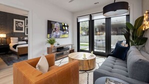 A modern living room with a sofa, a coffee table, a TV, and a ceiling fan. - Tria - 2 Condos - Odyssey (Nashville)