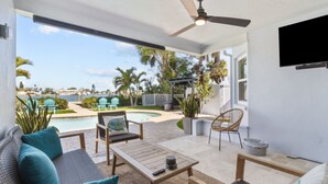 Un patio con piscina, mobiliario exterior y un ventilador de techo.