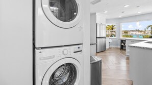 Un moderno cuarto de lavado con lavadoras y secadoras apiladas, vistas de la ciudad a través de grandes ventanales y un diseño limpio y minimalista.