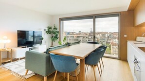 A modern apartment with a dining area, a TV, and a large window with a city view. - GuestReady - Central Park in Porto (Porto)