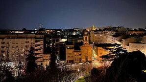 A nighttime view of a cityscape with various buildings, including a prominent church with a golden spire. - GuestReady - Central Park in Porto (Porto)