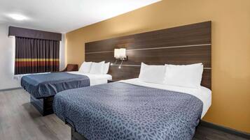 A hotel room with two beds, a wooden headboard, a nightstand, and a window with curtains.