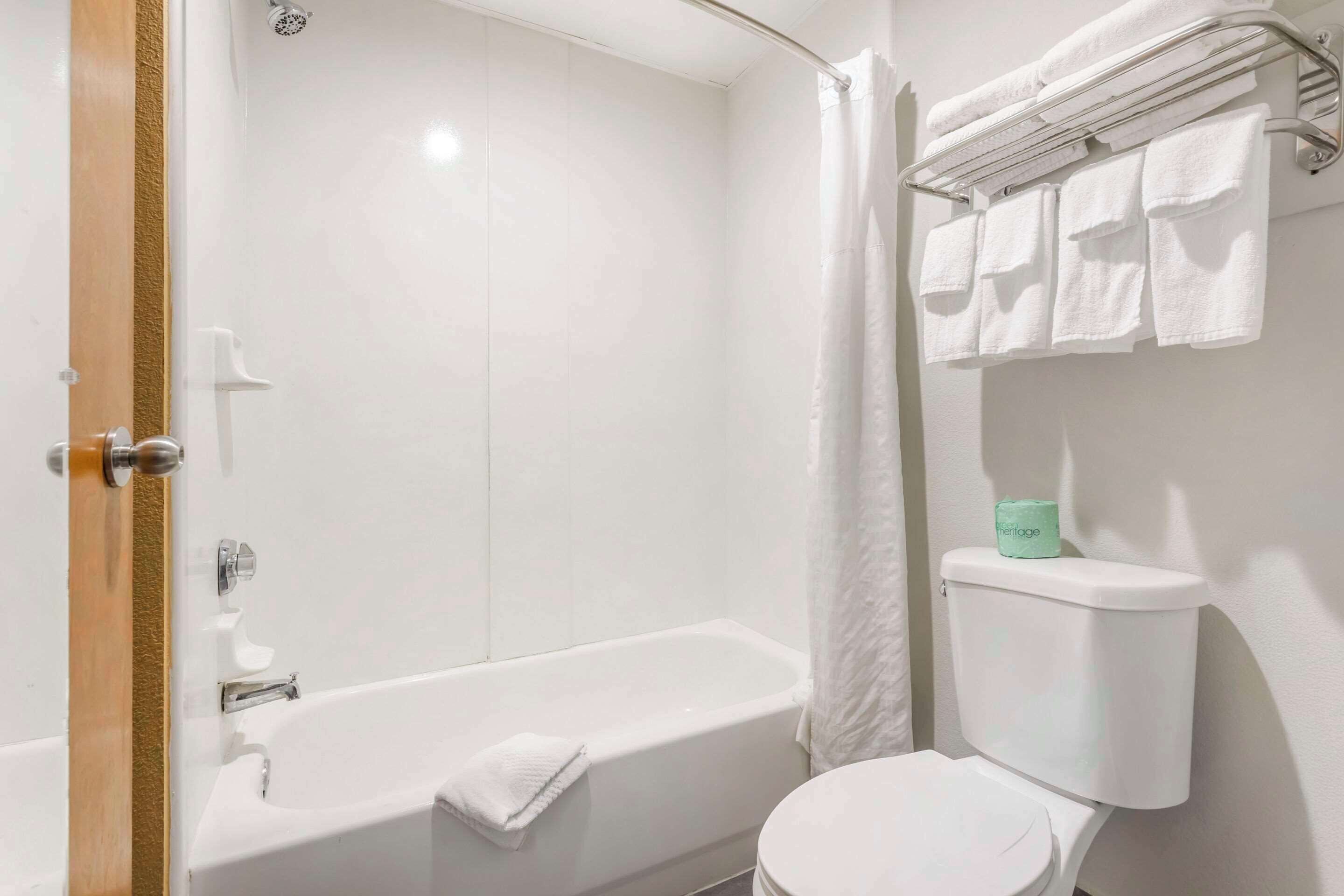 A bathroom with a bathtub, toilet, and towel rack.