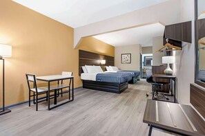 Een hotelkamer met een bed, een bureau, een stoel en een kapstok.