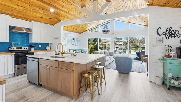 Une cuisine moderne dotée d’un grand îlot central, d’un plafond en bois et offrant une vue sur l’extérieur.