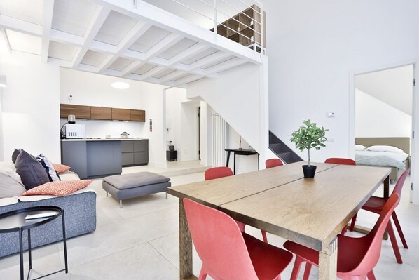 A modern interior with a dining area, kitchen, and a loft space.