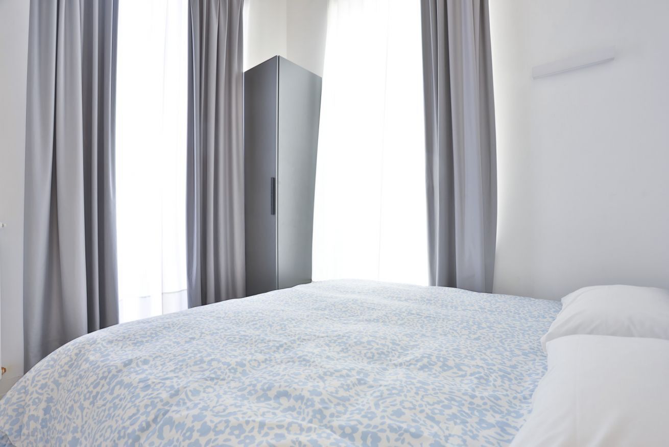Una camera da letto con un letto, un armadio e delle tende.
