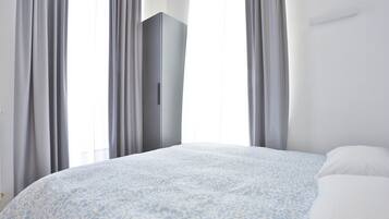 Una camera da letto con un letto, un armadio e delle tende.
