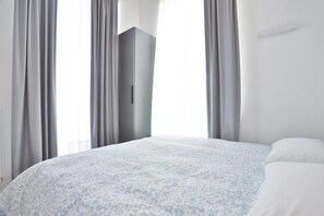 Una camera da letto con un letto, un armadio e delle tende.