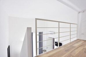 Ein modernes Zimmer mit Holzboden, weißer Wand und einer Schiebetür.