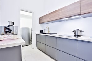 Une cuisine moderne avec des meubles gris, un évier en acier inoxydable et une machine à café.