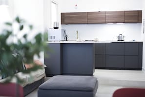 Une cuisine moderne avec des meubles de couleur sombre, un plan de travail blanc et un petit îlot central.