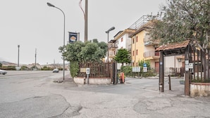 A street view with a gated entrance, a building with balconies, and a clear sky. - GuestHost - Cozy Studio x2 - w/ Balcony (Chianchitta)