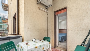A small balcony with a table and chairs, a view of the building, and a door leading to an interior room. - GuestHost - Cozy Studio x2 - w/ Balcony (Chianchitta)