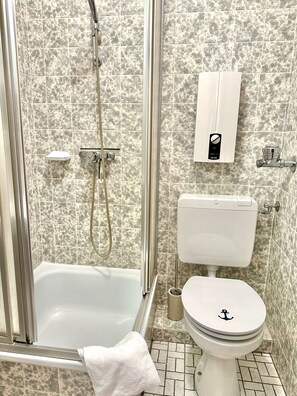 Ein Badezimmer mit Dusche, Toilette und einem Schrank mit Toilettenpapierhalter.