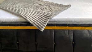 A bed with a black headboard, white bedding, and a grey throw blanket. - LuckySmallie 1-Bed Apartment in Goba,Dar es Salaam (Dar es Salaam)