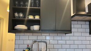 Una cocina con un lavaplatos de acero inoxidable, un lavavajillas empotrado y una campana extractora negra sobre la estufa.