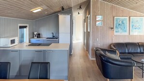 Eine moderne Küche mit Mikrowelle, Spüle und Schränken, ein Essbereich mit Tisch und Stühlen sowie eine Wohnbereich mit Sofa und Couchtisch.