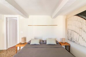 Een slaapkamer met een bed, twee nachtkastjes, een wandplank en een deur.