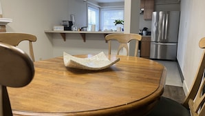 Ein Essbereich mit Holztisch und Stühlen, einer Kaffeestation und einer Küche im Hintergrund.