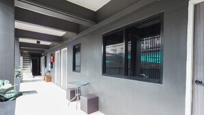 A corridor with a glass table and chairs, a fire extinguisher, and a door. - RQ Bangkok Huai Khwang by Collection O (Bangkok)