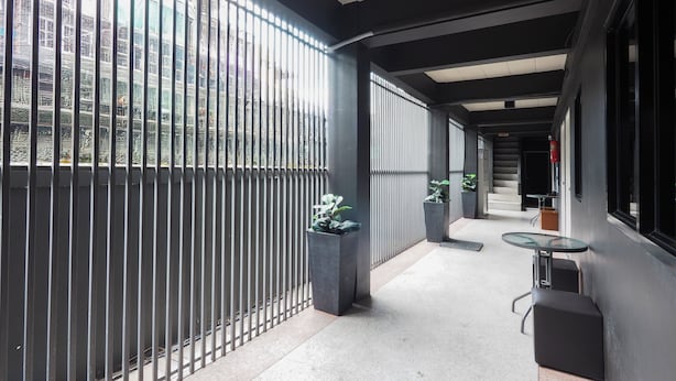 A corridor with a metal railing, potted plants, and a small table. - RQ Bangkok Huai Khwang by Collection O (Bangkok)