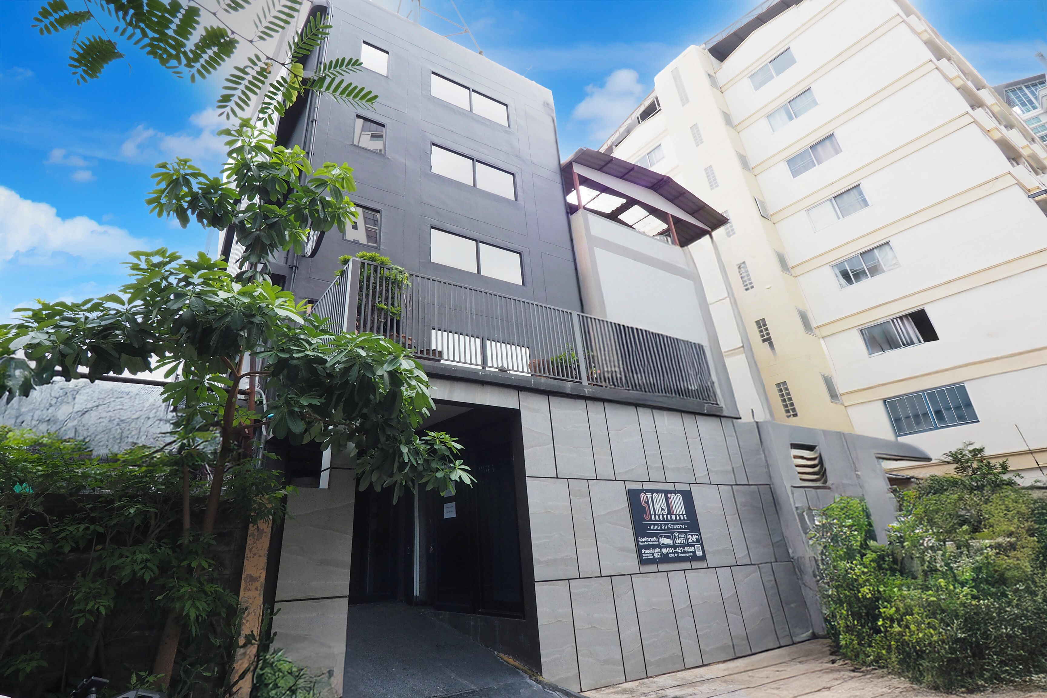 A multi-story building with a modern design, featuring a gated entrance and a balcony.