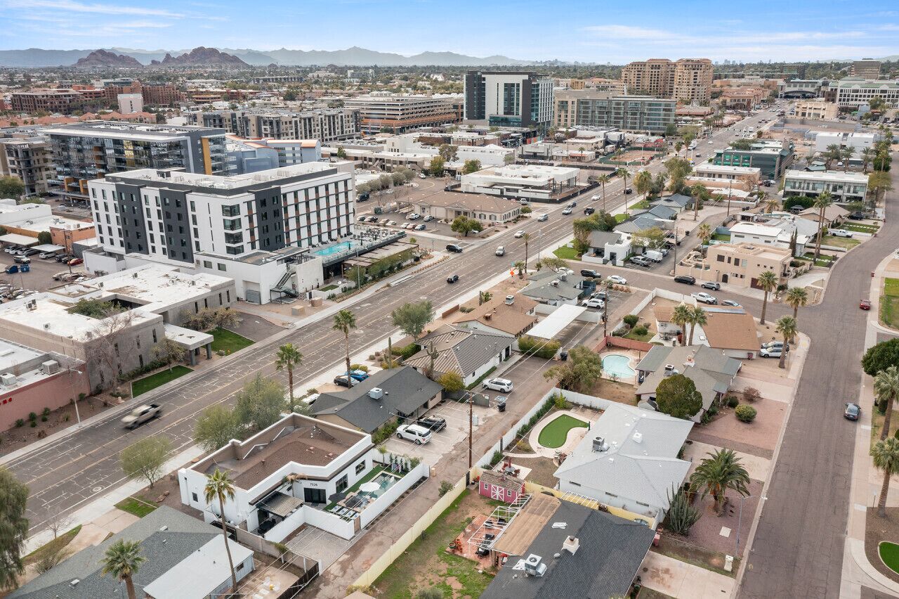 An urban street view with modern buildings, a mix of commercial and residential structures, and a clear sky.
