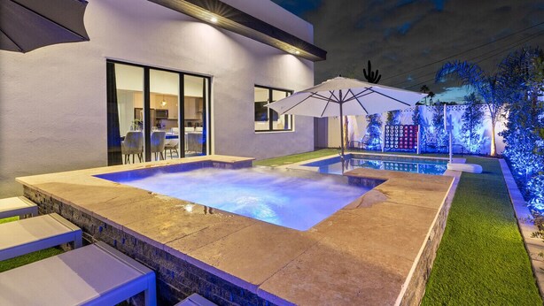 A modern outdoor pool area with a hot tub, surrounded by a patio with tables and umbrellas. - 6 Bedrooms, 9 Beds, 3 Bathrooms, an 82° Heated Pool, & the BEST 102° Spillover Hot Tub in all of Old Town Scottsdale! (Scottsdale)