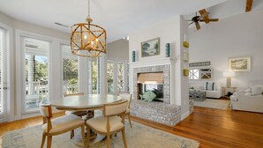 Un coin repas avec une table ronde et des chaises, une cheminée décorée de poissons et un ventilateur de plafond.