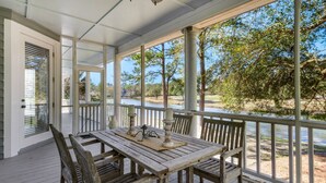 Une terrasse en bois avec une table et des chaises, d’où l’on a vue sur une rivière et des arbres.
