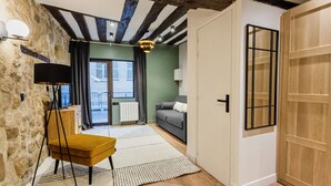 Un salón acogedor con una pared de piedra, techo de madera, un sofá, una lámpara y vistas a través de una ventana.