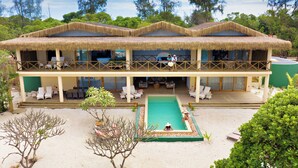 Un resort con piscina, sillas de descanso y un edificio con techo de paja.