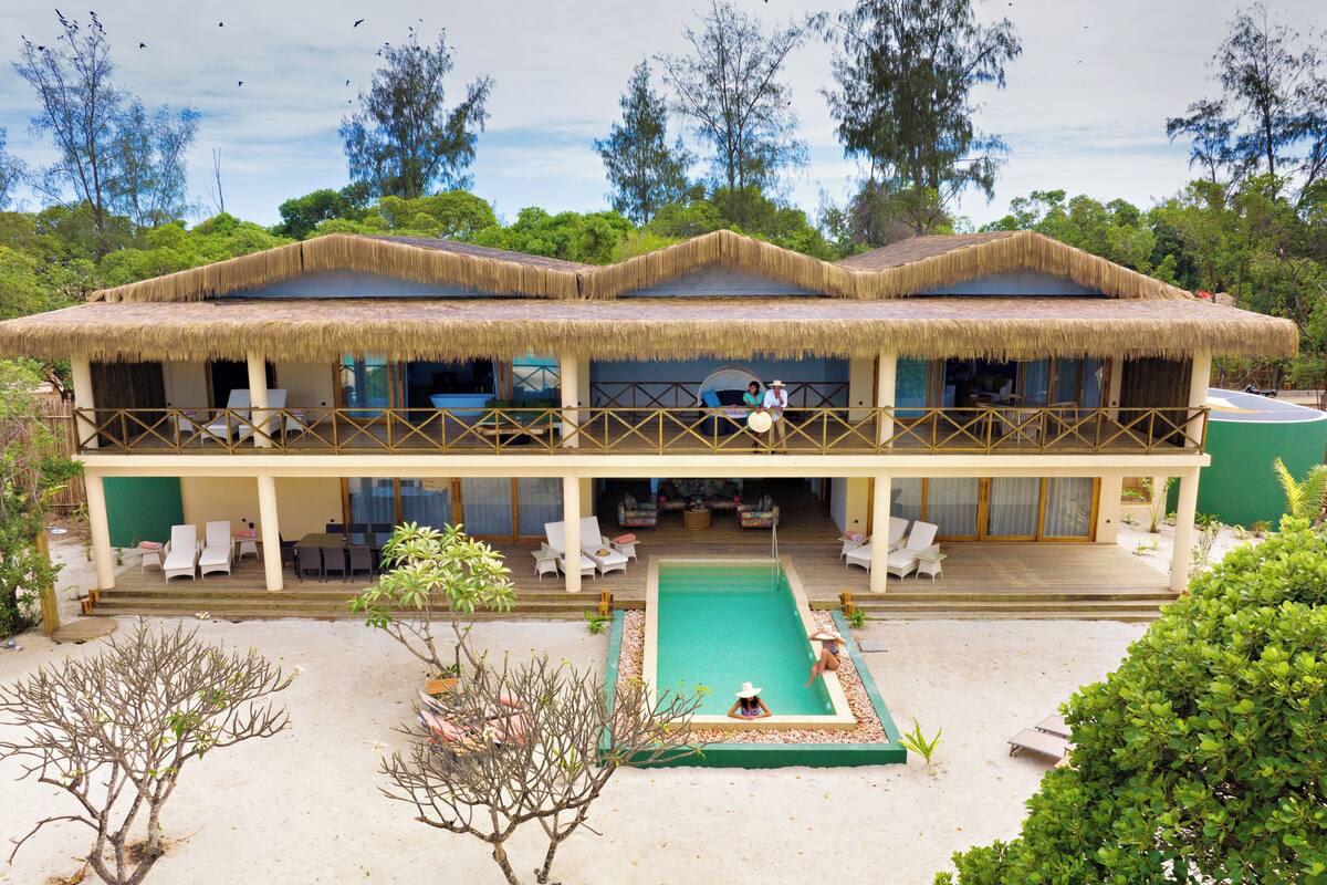 Ein Resort mit Pool, Liegestühlen und einem Gebäude mit Reetdach.