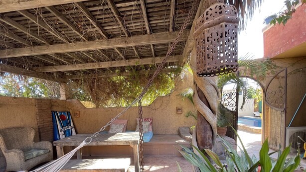 A rustic outdoor seating area with a hammock, wooden table, and chairs. - Amorito Guest house, Pool, 1 block from beach, 6 blocks from downtown  (Loreto)