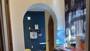 A kitchen with a water dispenser, a refrigerator, and a microwave. There is a blue wall with a shelf holding decorative items. - Amorito Guest house, Pool, 1 block from beach, 6 blocks from downtown  (Loreto)