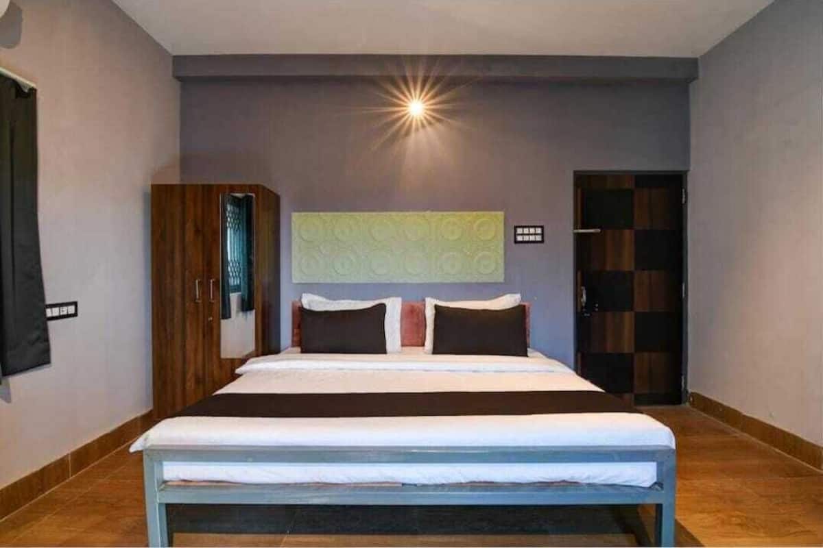 A hotel room with a large bed, a wardrobe, a mirror, and a door.