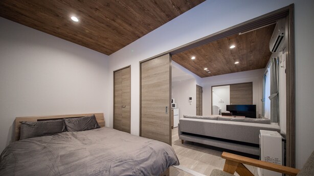 Un dormitorio con cama, sofá, televisor y espejo.