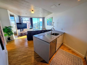 Una cocina moderna con isla integrada, televisor de pantalla plana y un amplio ventanal con vista a la ciudad.