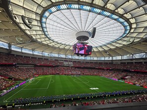Un estadio con una amplia estructura de techo circular y un marcador central.