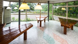 Une pièce dotée de grandes fenêtres, d’un banc en bois et d’une table.