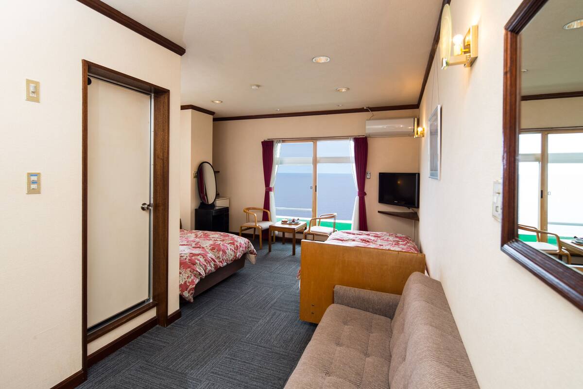 Une chambre d’hôtel avec deux lits, un canapé, un bureau et une télévision.