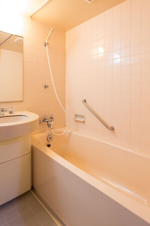 A bathroom with a bathtub, a sink, and a handrail. - Oyashirazu Kanko Hotel (Itoigawa)