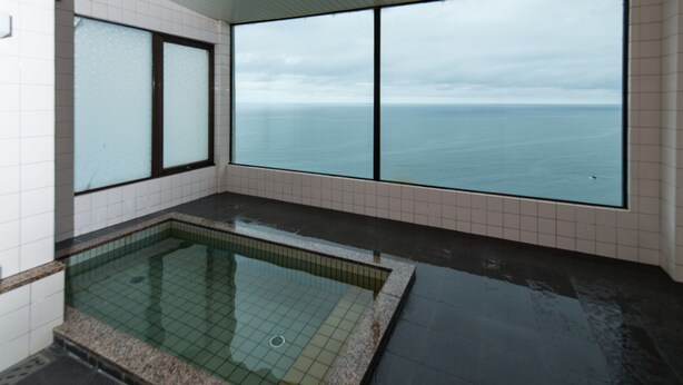 Une piscine intérieure moderne avec de grandes baies vitrées offrant une vue sur la mer.