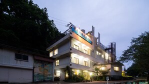 Un hôtel à plusieurs étages doté d’un balcon au dernier étage, d’un garage au rez-de-chaussée et d’une fresque murale sur le côté du bâtiment.