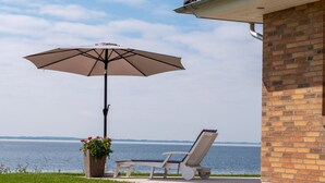 Patio con una poltrona da relax e un ombrellone con vista su un corso d'acqua.