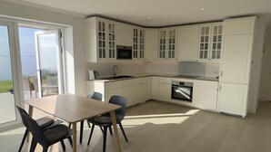 Una cucina moderna con mobili bianchi, un tavolo da pranzo con sedie e vista sull'esterno.
