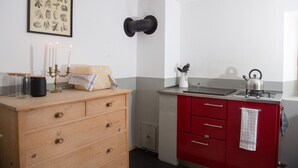 Een keuken met een houten dressoir, een rode kast, een waterkoker en een lijst met een botanische afbeelding aan de muur.