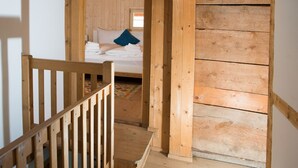 Een houten trap die leidt naar een slaapkamer met een bed, kussens en een blauw kussen.