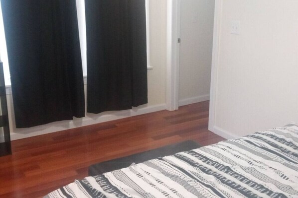 A room with a bed, a door, and a window with black curtains. - king size one bed room (Schenectady)